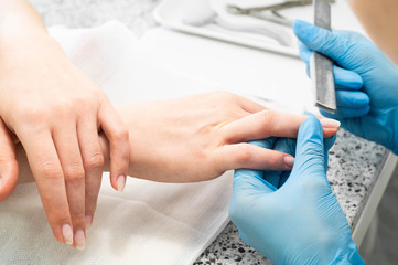 Nail technician giving a customer a manicure at nail salon. Young caucasian woman receiving a manicure. Closeup shot of a woman doing manicure