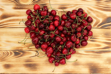 ripe natural cherry berries on a wooden tray in the shape of a heart