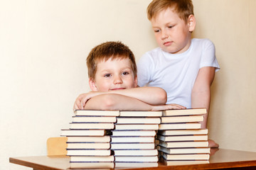 two boys in white t-shirts at the table with books. school