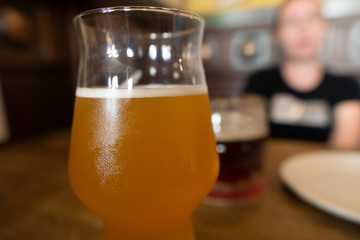 Mug of cold beer with misted glass.  Girl in blur on background.