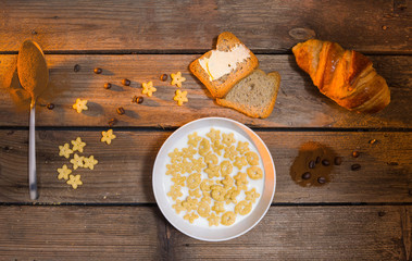 Breakfast on a rustic table with coffe, milk, croissant and toast with butter