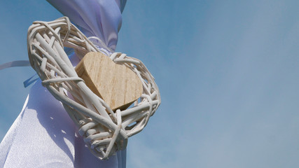 Two wooden rustic decorative hearts hanging on a wedding arch - blue sky in the background