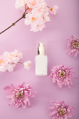 Obraz na płótnie Canvas Skin care cosmetics bottle. Flowers pink background