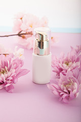 Skin care cosmetics bottle. Flowers pink background