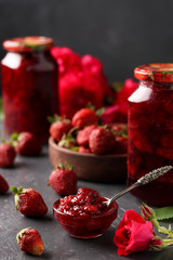 Strawberry jam in a can and fresh strawberries on a dark background, summer harvest