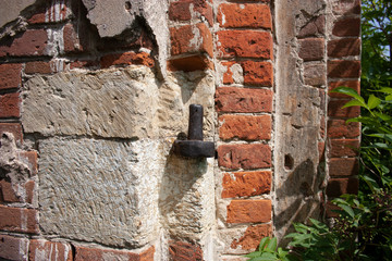 Rusty loop on the wall of an ancient temple close-up. Wall of white stone and red brick closeup.