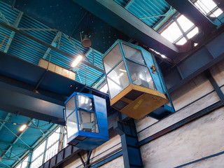 Looking up to two crane cockpits in a clean looking industry environment