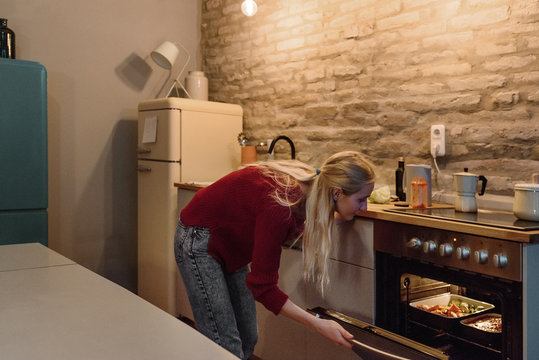 Woman checking meal in oven