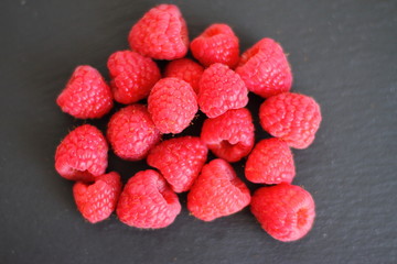 fresh pink raw raspberries on black slate background