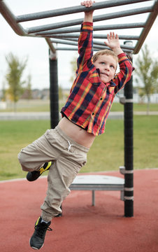 A young boy swinging on monkey bars at a playground