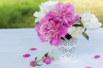 Beautiful soft pink peonies in vase on white wooden background outdoors. Summer flowers in blossom. Nature, fresh pink flowers concept