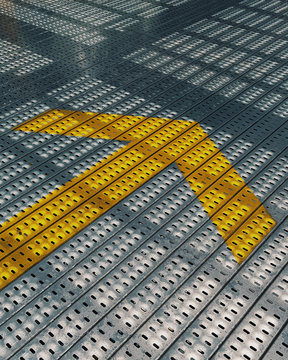 Yellow arrow on steel ramp of a parking lot.