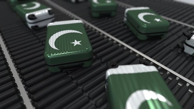 Many travel suitcases featuring flag of Pakistan on roller conveyer. Pakistani tourism conceptual animation