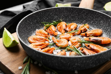Frying pan with tasty shrimps on table