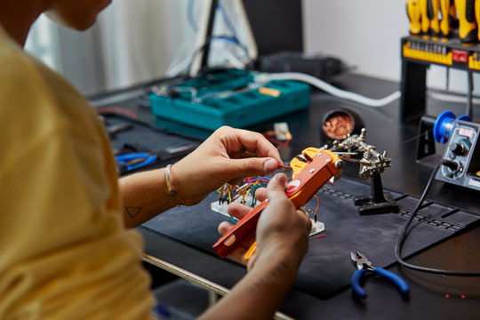 Engineer Stripping Wire With Equipment At Desk