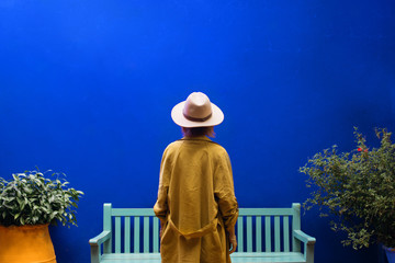 Woman In Hat  Stands By Blue Wall