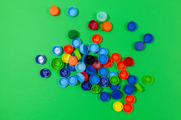 Bottle caps are laying on a green surface 