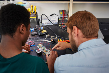 Teacher Explaining Student While Working On Device