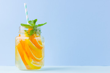 Infused water with fruits on blue background. Mug delicious refreshing drink of mix fruits with mint on blue background. Iced summer drink in mason jar. Minimalism
