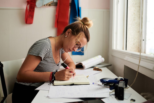 Student in glasses and earphones taking notes.