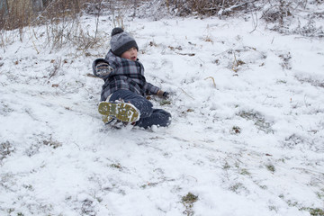 ride on the buttocks in the snow,happy boy riding his legs and buttocks in the winter on snow