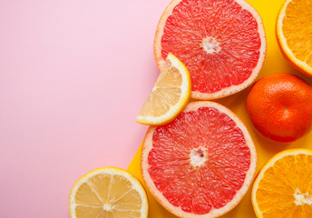Flat lay of cut ripe juicy grapefruit, lemon and orange on pink background with copyspace.