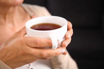 Mature woman drinking coffee at home, closeup