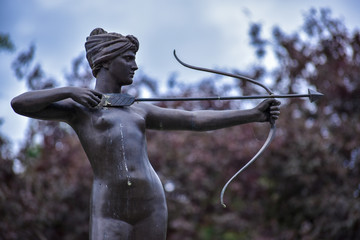 Statue of the naked lady who is holding a bow and arrow and aiming for target