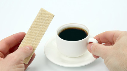 two hands with a Cup of black coffee and waffle.