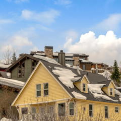 Square Houses on snow covered ground against blue sky with puffy clouds in winter