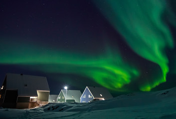 Arctic village and green waves of Northern lights over Inuit houses, in a suburb of Nuuk, Greenland © vadim.nefedov