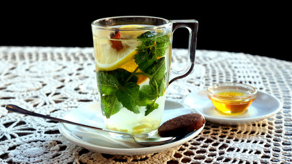 Cup of tea with lemon, mint, ginger and dessert.