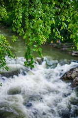 A stream in the mountains flows along the rocks and a stormy waterfall