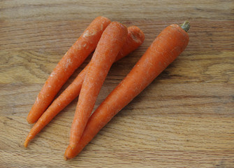 Four topless carrots on an oak cutting board