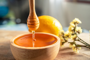 Healthy organic scoop Thick honey dipping with wooden honey spoon from a wooden bowl, honey...