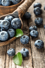 Blueberries in wooden spoon on old wood table. Healthy eating and nutrition concept.