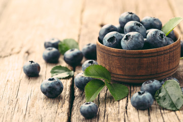 Freshly picked blueberries in wooden bowl on wooden background. Healthy eating and nutrition.