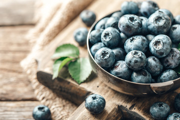 Freshly picked blueberries in bowl on wooden background. Healthy eating and nutrition.