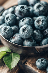 Freshly picked blueberries in bowl on wooden background. Healthy eating and nutrition.