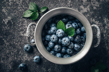 Freshly picked blueberries in  bowl on old metal background. Healthy eating and nutrition.