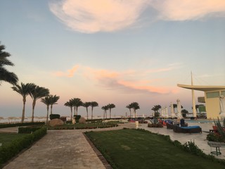 Sunset beach tropical travel resort, enjoying summer holidays vacation concept image. Modern hotel building alley with palms, sky, blue heaven palm tree area. Sharm El Sheikh, Egypt, Africa