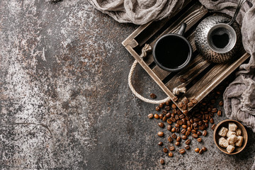 Coffee on wooden tray with coffee beans on dark textured background. Top view with copy space. Background with free text space.