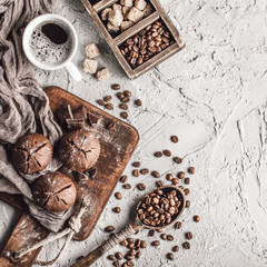 Coffee beans with coffee and muffins on grey textured background.