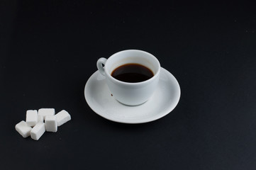 White coffee cup with sugar cubes isolated on a black background
