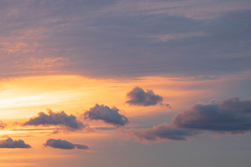 Puffs of clouds against beautiful orange and blue sky in background at sunset