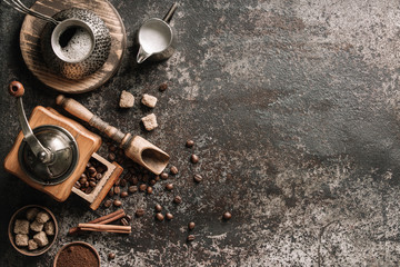 Fototapeta na wymiar Coffee cup with coffee grinder and coffee beans on dark textured background.