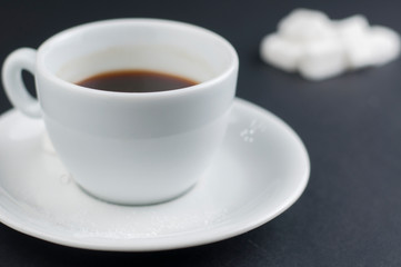White coffee cup with sugar cubes isolated on a black background