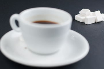 White coffee cup with sugar cubes isolated on a black background