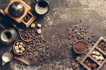 Coffee cup with coffee grinder and coffee beans on dark textured background.
