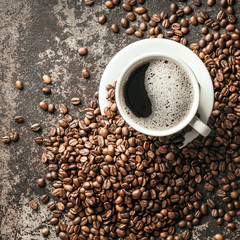 Coffee cup and coffee beans on dark stone background..